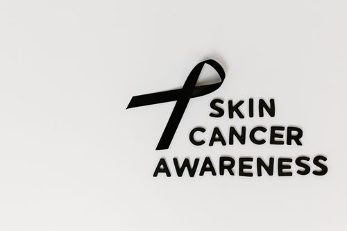 Free Minimalist image promoting skin cancer awareness featuring a black ribbon symbol on a white backdrop. Stock Photo