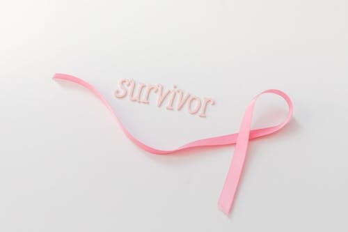 Pink Letters Beside a Ribbon on a White Surface