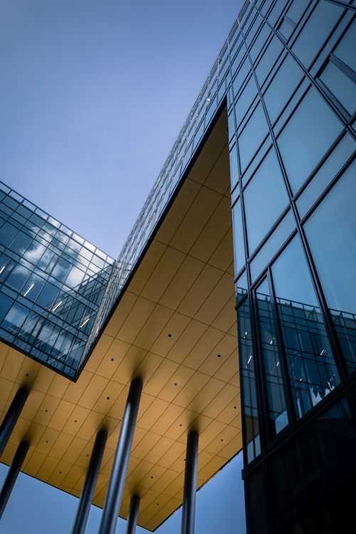 Free Low angle shot of a modern glass building showcasing a futuristic design with reflective facades. Stock Photo