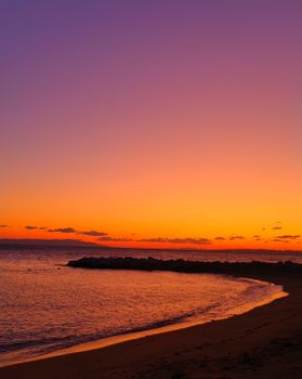 Breathtaking sunset casting vibrant hues over the ocean and beach. Tranquil and serene scene.