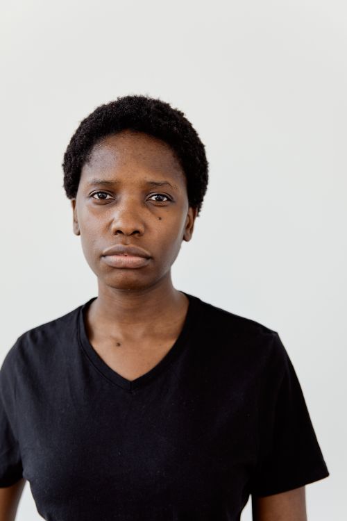 Free Close-up portrait of a young woman in a black shirt against a white background, conveying a neutral expression. Stock Photo
