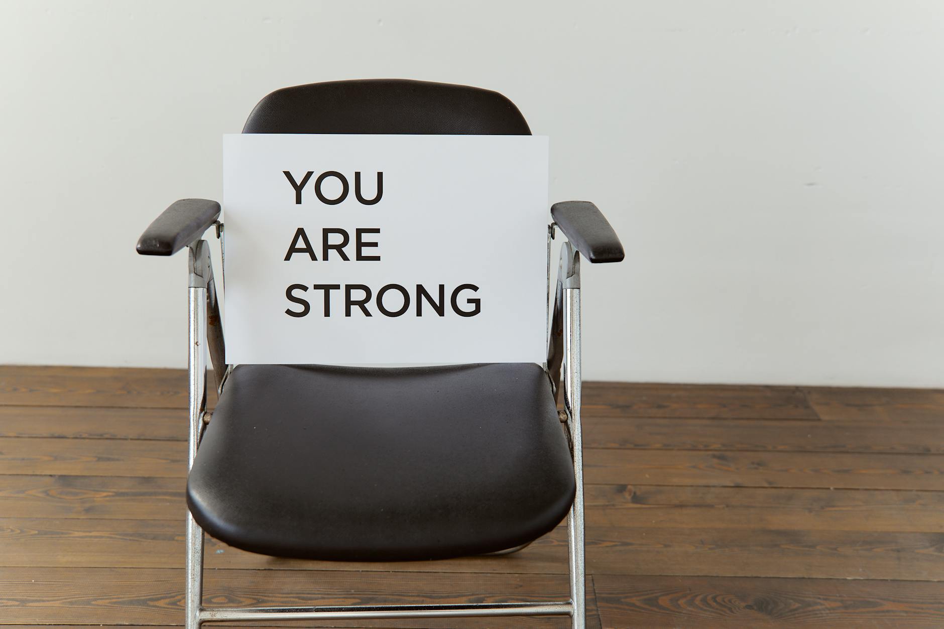 Black chair with 'You Are Strong' sign, symbolizing resilience.