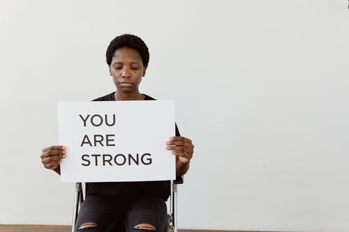 Free Woman holding 'You Are Strong' sign, promoting empowerment and motivation. Stock Photo