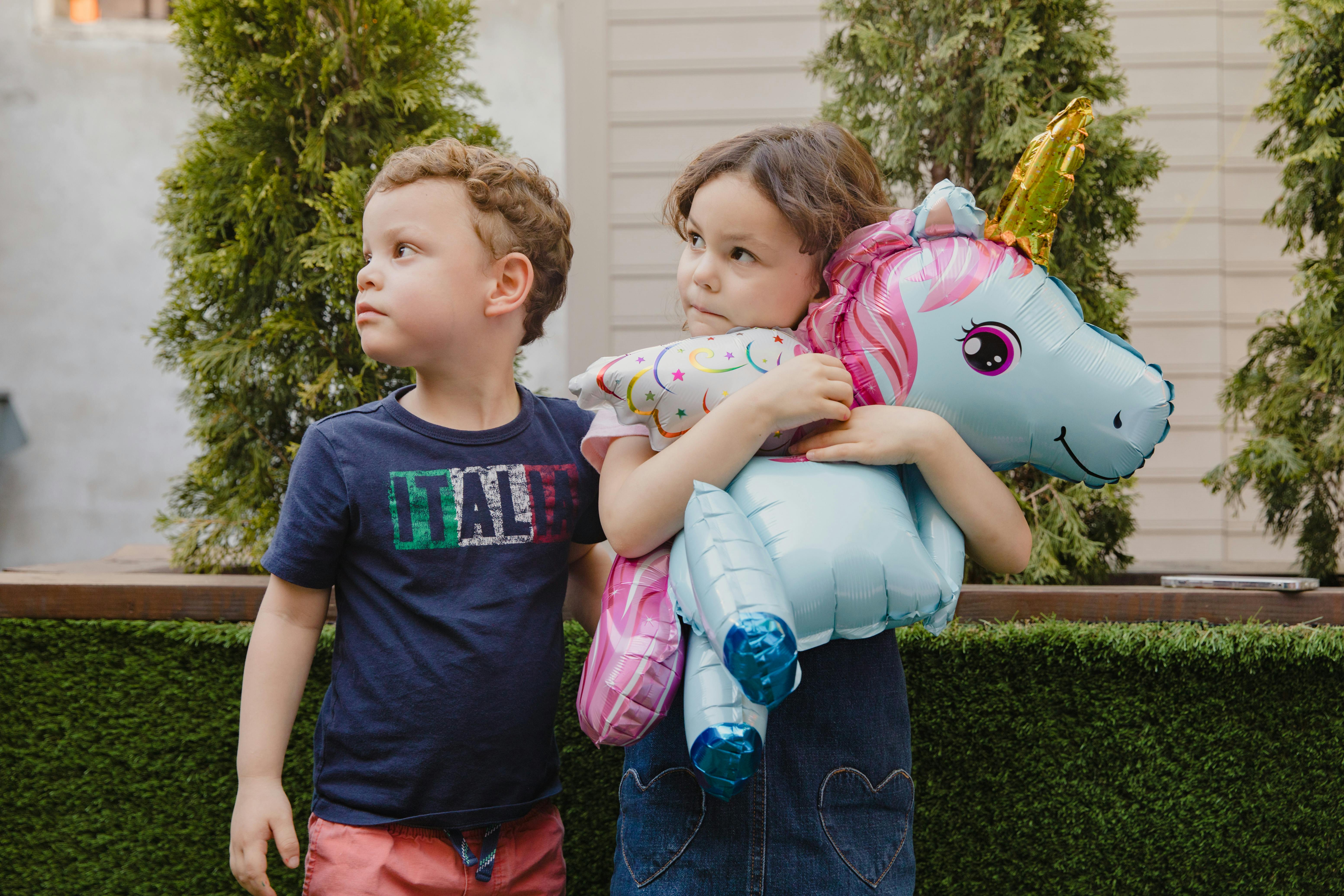 girl holding balloon beside a boy