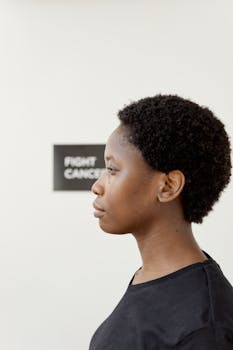 Profile portrait of a woman with afro hair in a black t-shirt supporting cancer awareness with a conceptual message.