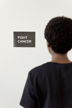 A person stands facing a 'Fight Cancer' sign, promoting awareness and motivation.