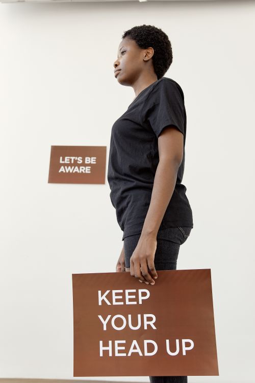 Free Side profile of a person holding a sign with a powerful message promoting awareness and positivity. Stock Photo