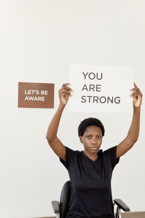 Free African American woman holding positive message signs for strength and awareness. Stock Photo