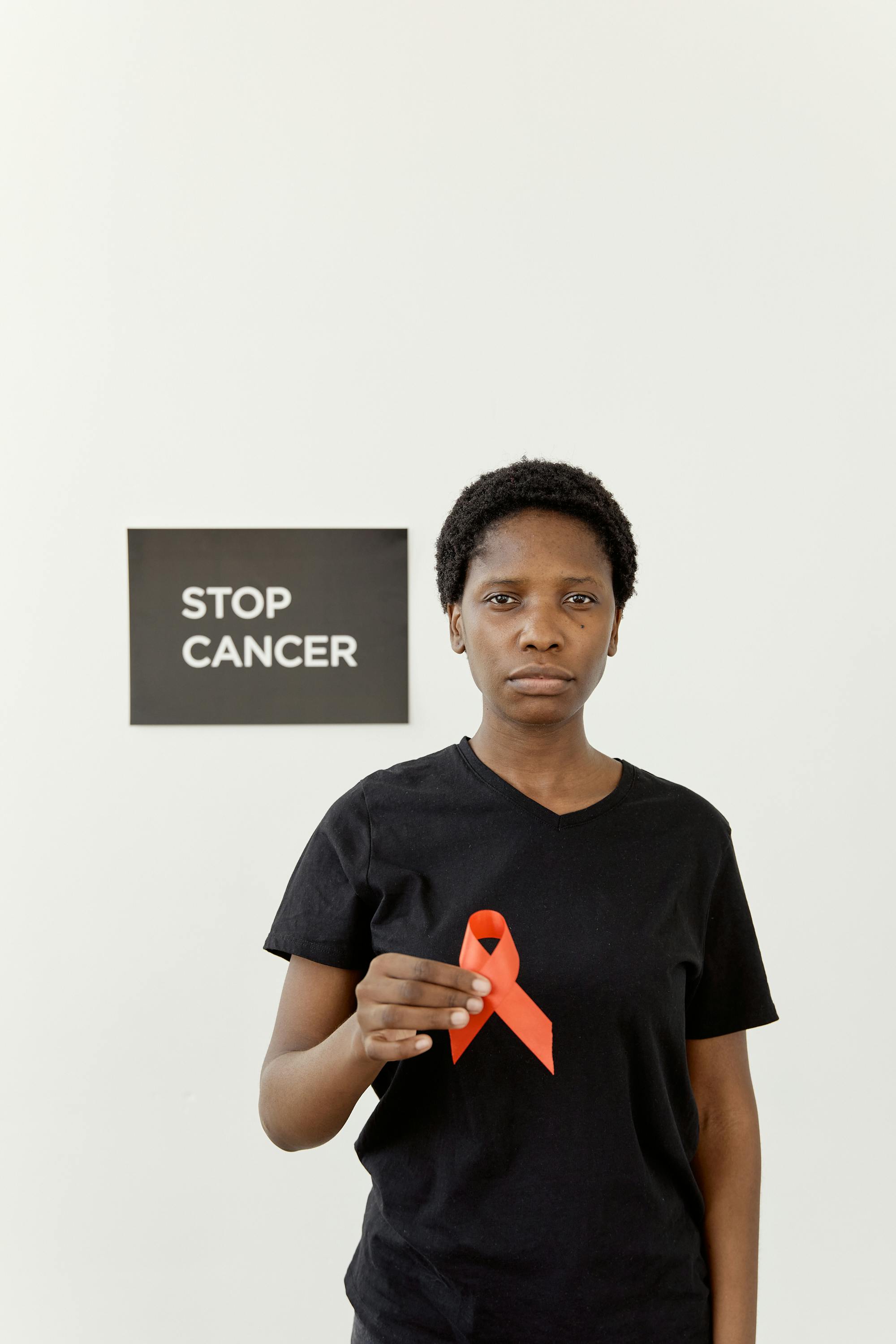 African American woman holding ribbon promoting cancer awareness.