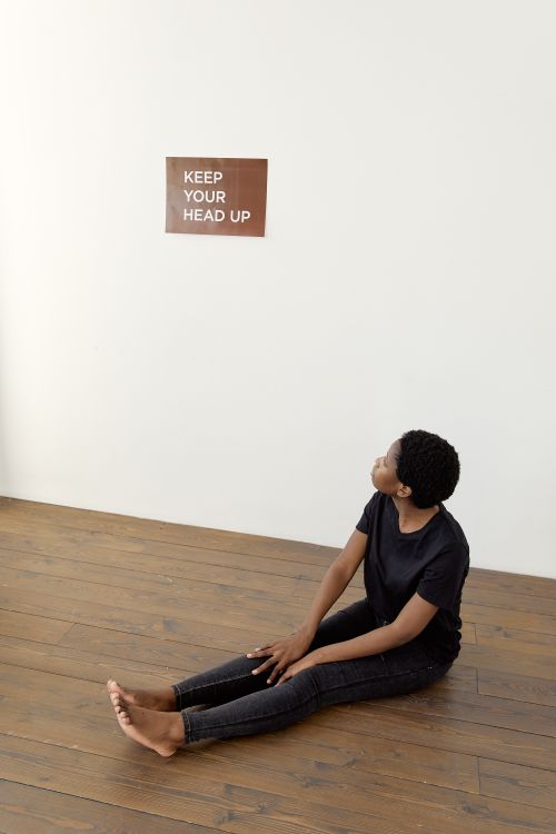 Free A woman sits on the floor looking at a motivational sign on the wall. Stock Photo