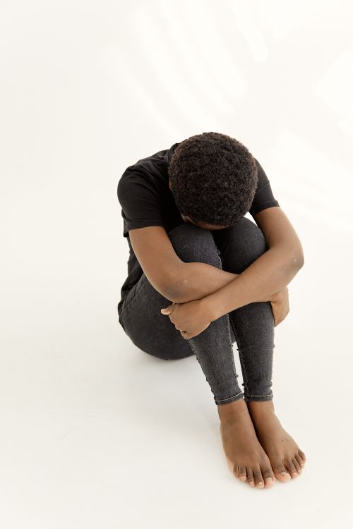 Free A thoughtful pose of a woman curled up on a white background, conceptually exploring themes of introspection and mental health. Stock Photo