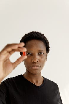 A strong portrait of a woman holding a red pill symbolizing health or treatment.