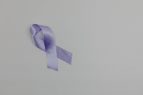 Lavender ribbon representing cancer awareness and support for people with disease placed on white background with copy space in light studio