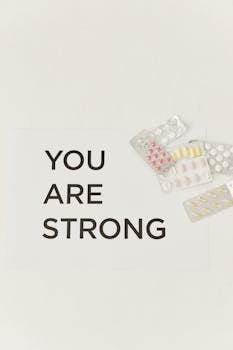 Medication packets with 'You Are Strong' message on a clean white backdrop, symbolizing resilience.