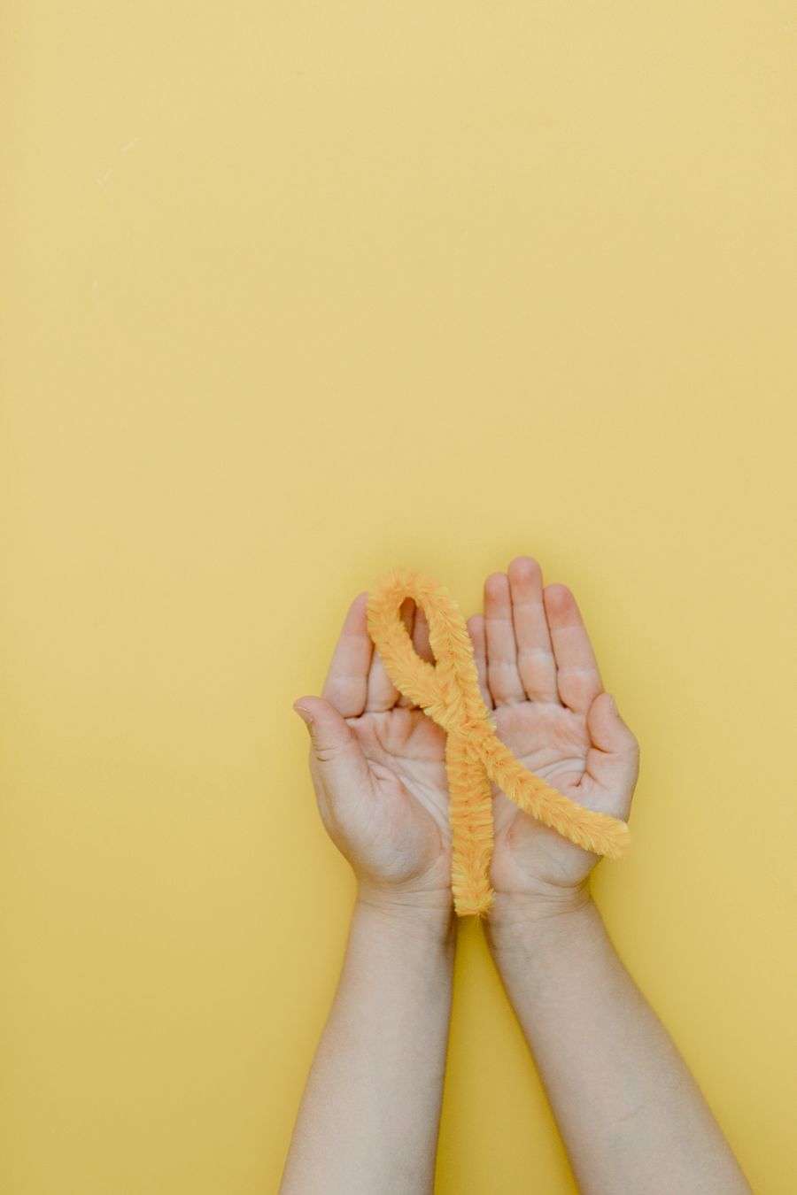 Hands holding a gold cancer awareness ribbon