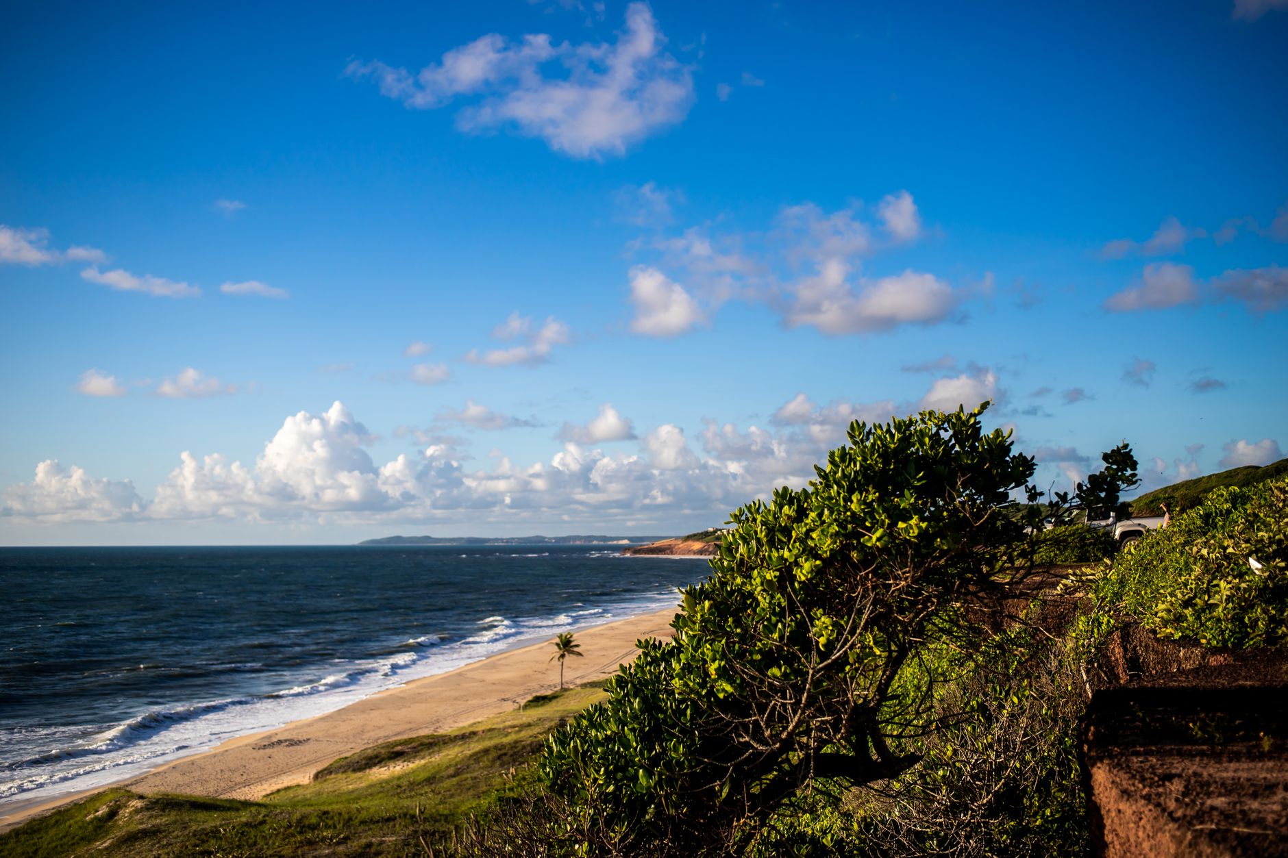 Idyllic coastal view of Pipa Beach in Brazil with clear skies and lush greenery.