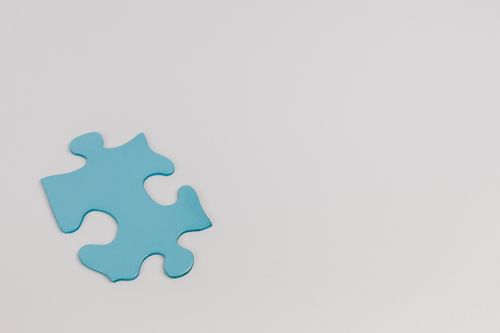 Free Minimalist photo of a single blue puzzle piece on a white background symbolizing autism awareness. Stock Photo