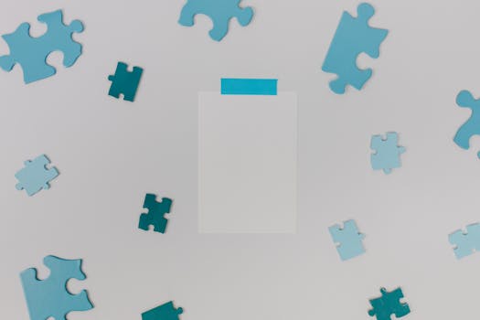 Flat lay of various blue puzzle pieces scattered on a white background with copyspace.
