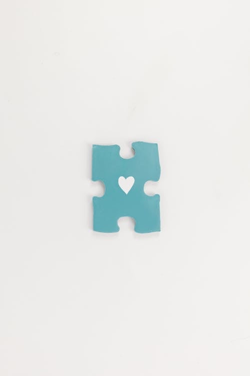 Blue Puzzle Piece with a Heart in the Middle Lying on White Background 