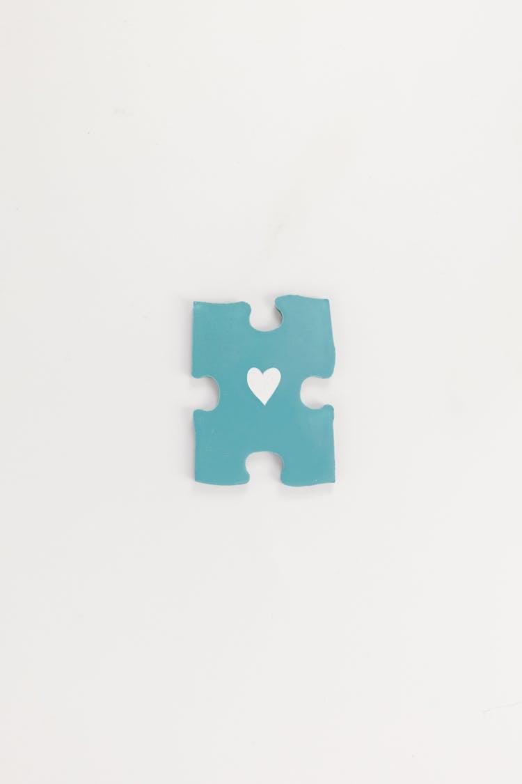 Blue Puzzle Piece With A Heart In The Middle Lying On White Background 