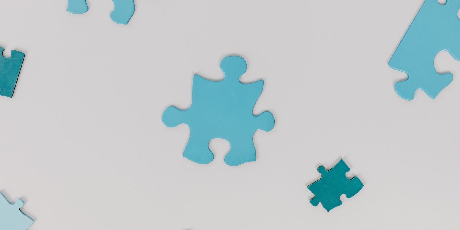 Light blue jigsaw puzzle pieces scattered on a white surface
