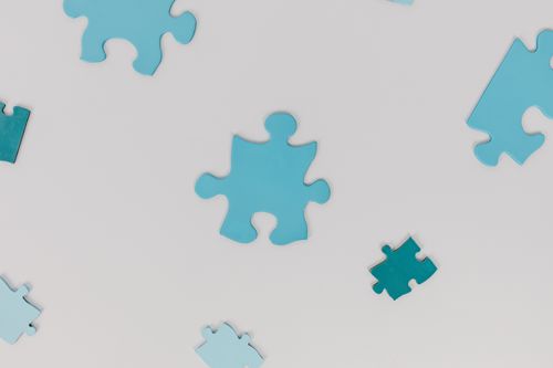 Free Scattered blue puzzle pieces on a white surface, symbolizing autism awareness. Stock Photo