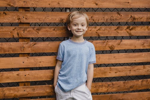 Free Young Boy standing against Wooden Panels  Stock Photo