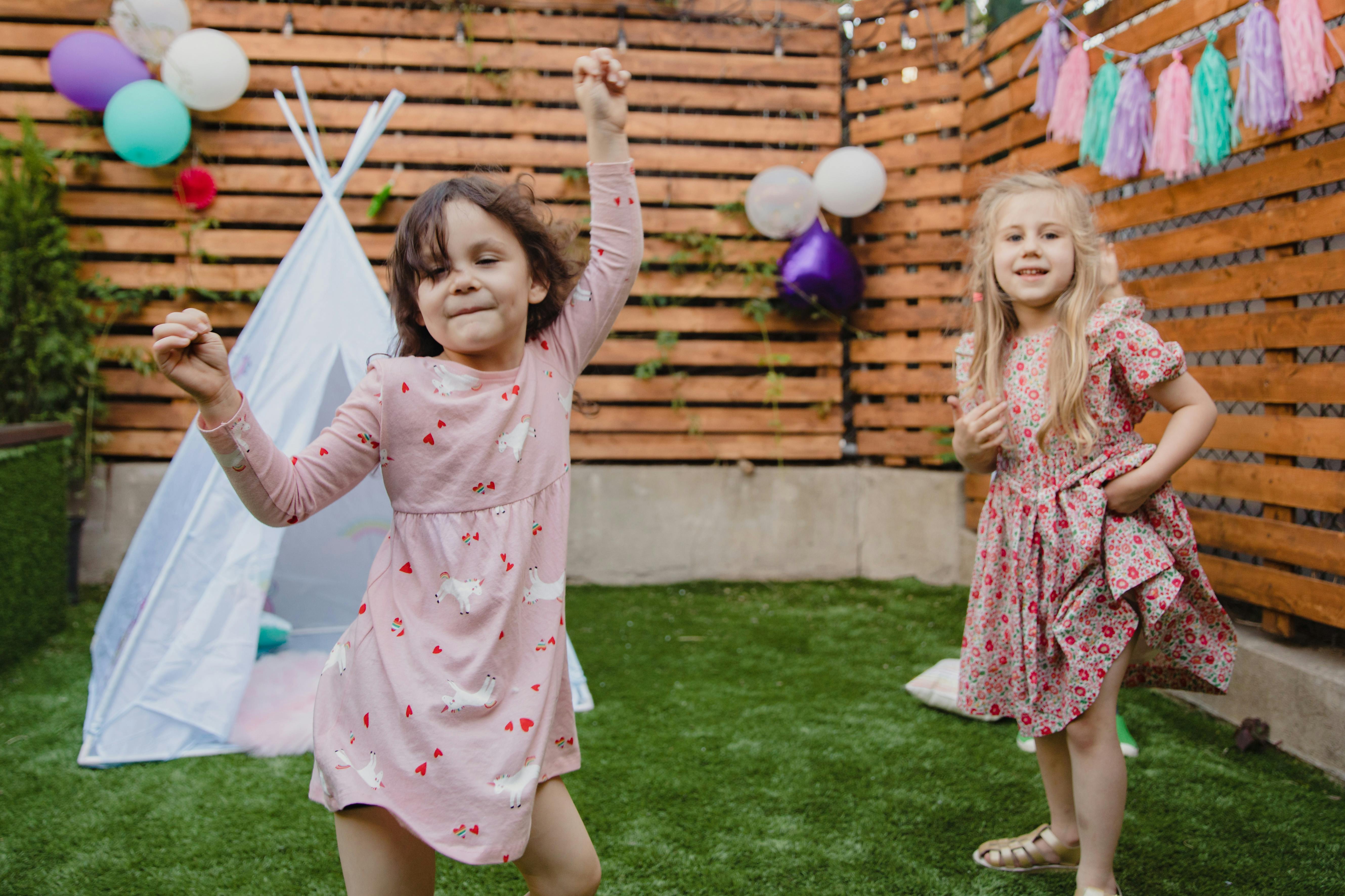 girls in pink and red dress on green grass