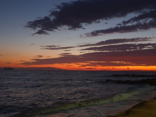 Free Gorgeous sunset over the ocean with vivid orange and red skies, highlighting tranquil waves. Stock Photo