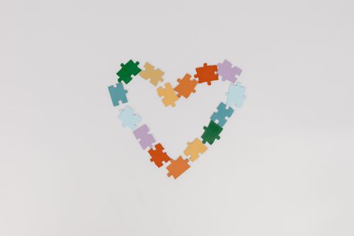 Free A vibrant heart shape formed with colorful puzzle pieces on a white background, representing love and unity. Stock Photo