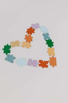 Colorful puzzle pieces forming a heart shape on a white background.