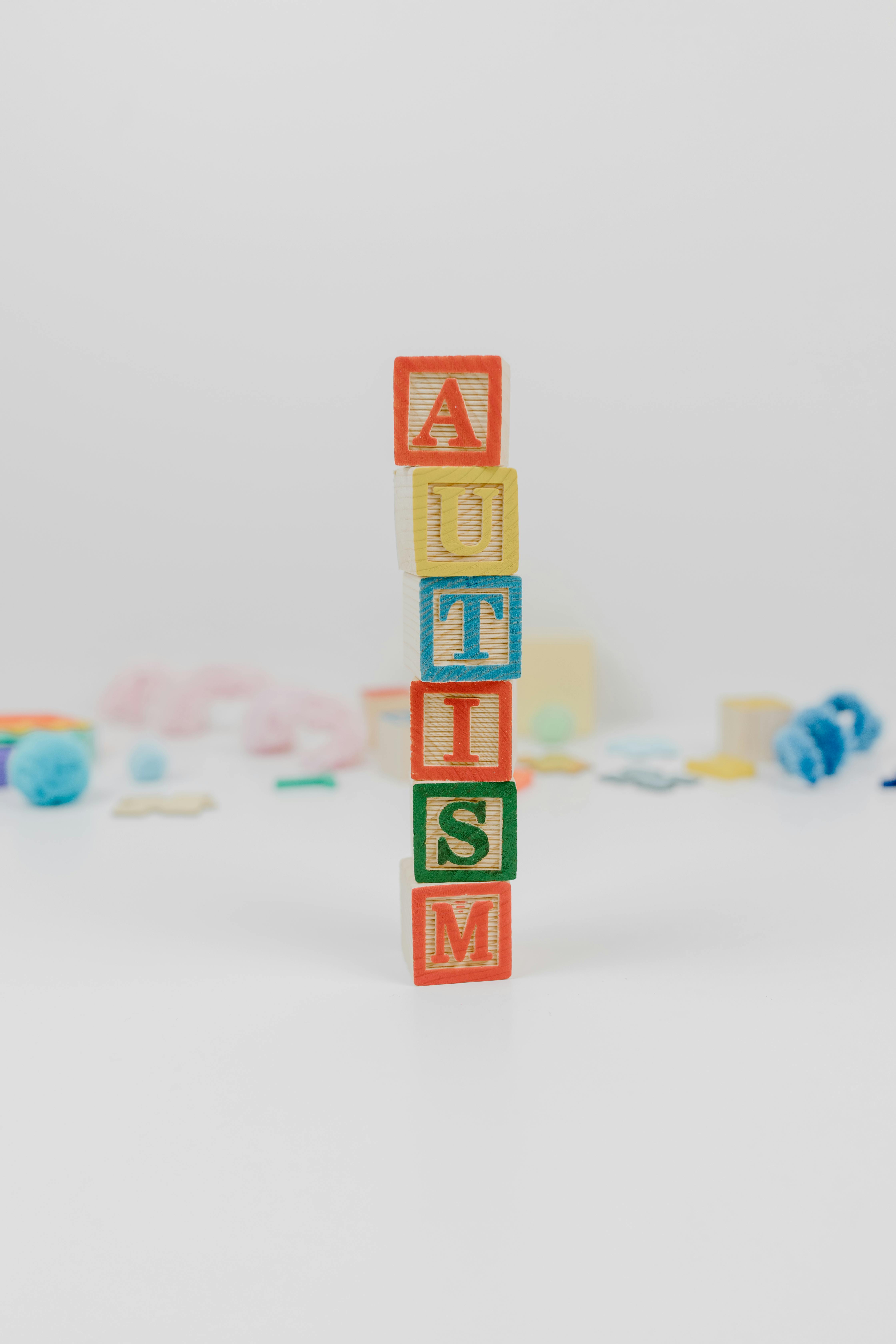Colorful wooden blocks arranged to spell 'Autism' on a white background, symbolizing awareness.