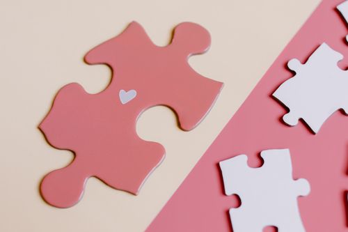 Free Close-up of a pink jigsaw puzzle piece with a heart, representing the concept of unity and connection. Stock Photo