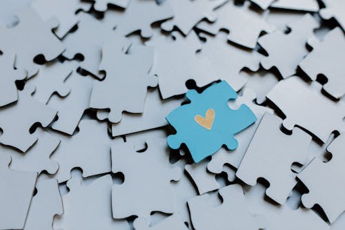 Free A Puzzle Piece with Heart Shaped Icon on the Pile of Puzzle Pieces Stock Photo