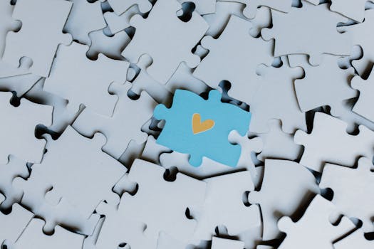 A standout blue puzzle piece with a heart symbol among white puzzle pieces, showing uniqueness.