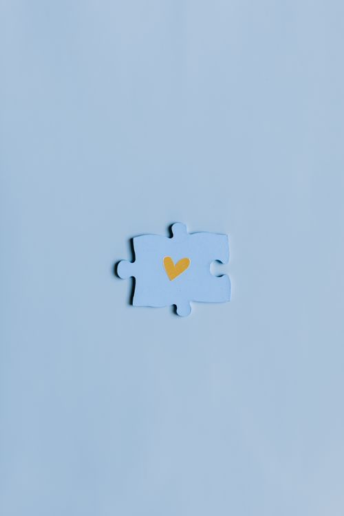 Free A close-up shot of a single blue puzzle piece with a yellow heart on a matching background. Stock Photo