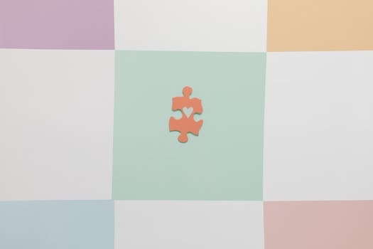 Top view of a vibrant puzzle piece with heart cutout, promoting autism awareness on a pastel grid background.