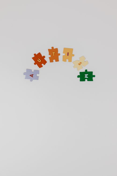 Free Colorful puzzle pieces spelling 'autism' on a white background symbolizing autism awareness. Stock Photo