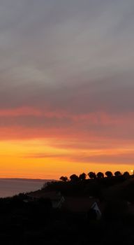 Scenic view of a vibrant sunset over a coastal silhouette, creating a picturesque horizon.