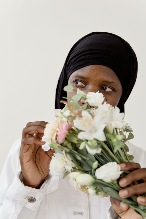 Free Portrait of an African woman wearing a hijab, smiling and holding a bouquet of flowers. Stock Photo