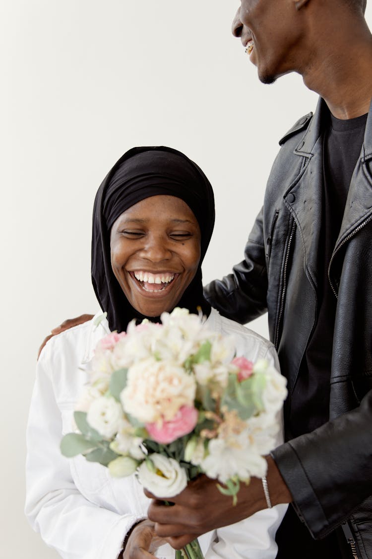 Woman Smiling While Receiving A Bouquet Of Flowers