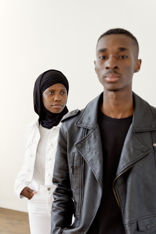 A Woman with Black Hijab Standing Behind the Man with Leather Jacket 