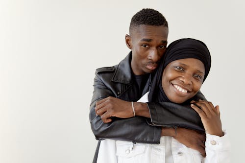 Man in Black Leather Jacket Embracing Woman in Hijab From Behind