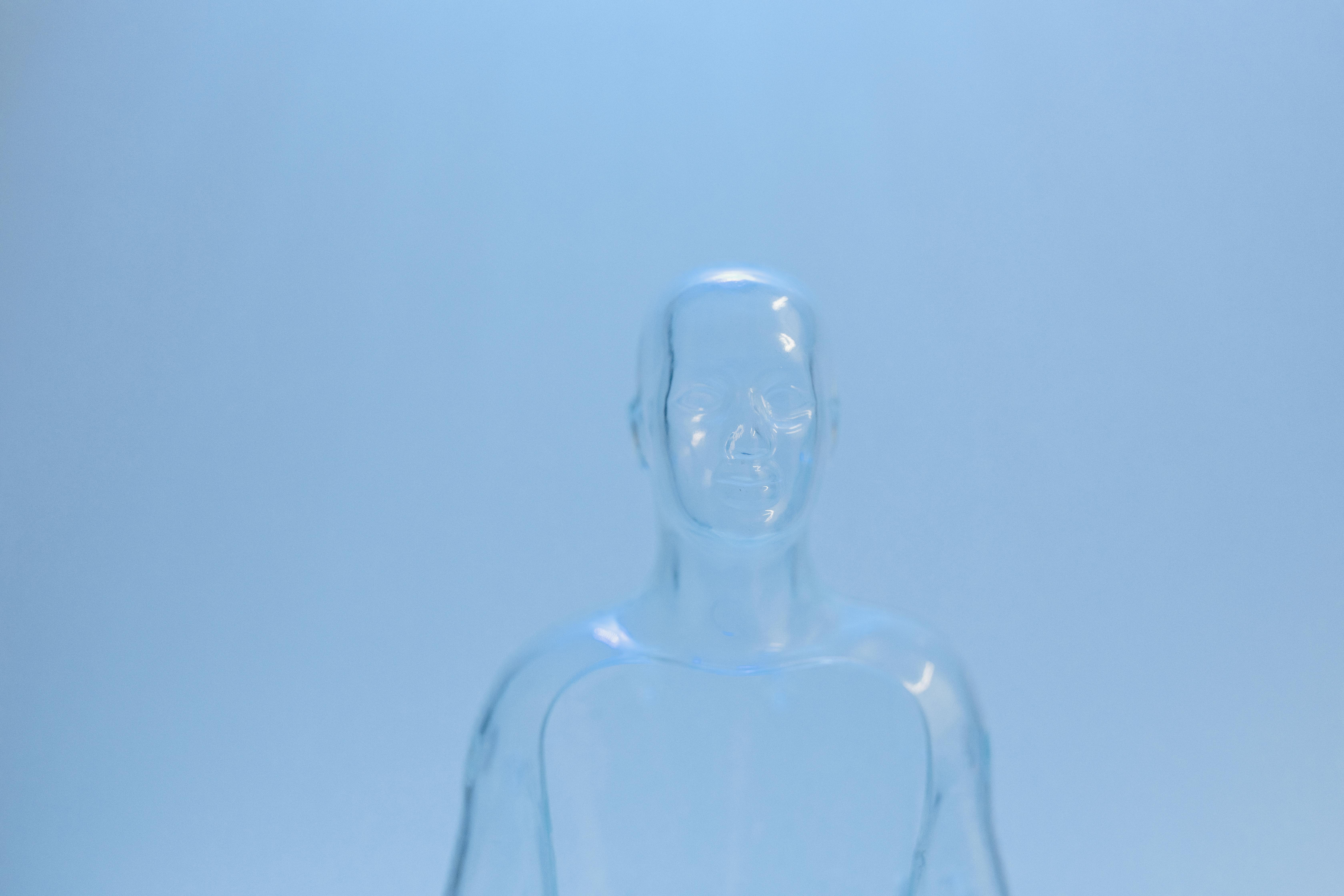 Futuristic transparent mannequin figure against a soft blue backdrop, evoking a sense of modern technology.