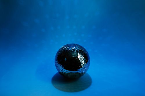 Free A disco ball casting shimmering reflections on a blue background, evoking a dance party vibe. Stock Photo