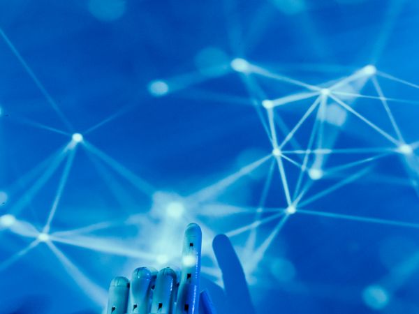 AI robot hand reaching into a blue neural network