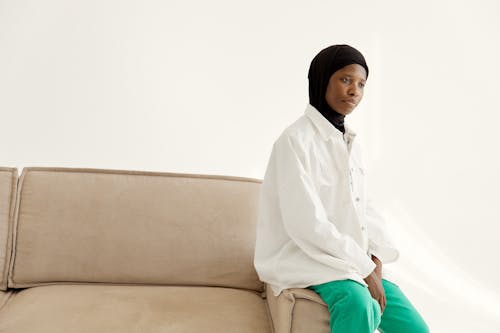 Woman in Hijab and White Long Sleeves Sitting on Armrest