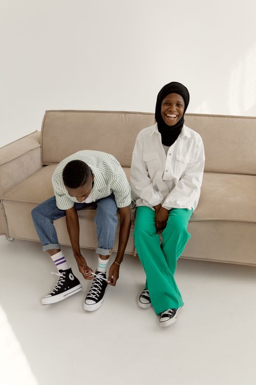 Free A cheerful couple sitting on a sofa, sharing a joyful moment indoors. Perfect for lifestyle or happiness themes. Stock Photo