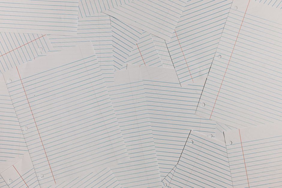 Overhead view of scattered blank lined paper sheets creating a textured background.