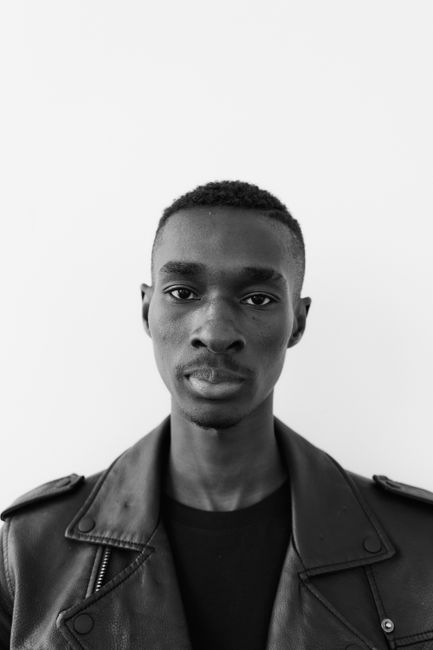 A striking black and white portrait of a man wearing a leather jacket, exuding a serious expression.